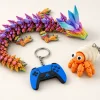Dragon Crystal multicolore, figurine de bernard-l’hermite orange et porte-clés manette bleu sur fond ivoire.